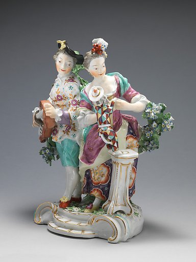 Youth playing hurdy-gurdy, girl teaching dog dressed as harlequin to dance