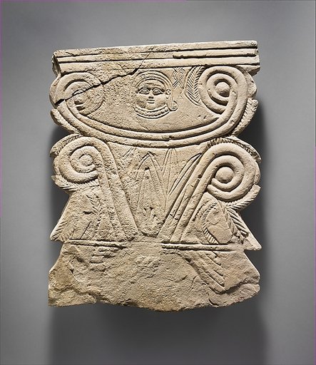 Limestone funerary stele with volutes and a Hathor head