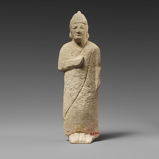 Limestone statuette of a beardless male votary with a conical helmet