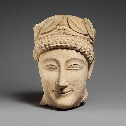 Limestone head of a beardless male votary with a wreath of leaves