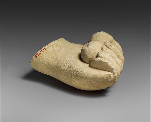 Limestone hand holding a disk and pieces of fruit