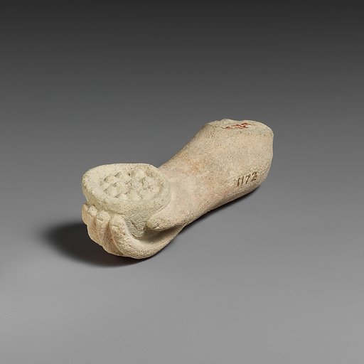 Limestone arm with pieces of fruit (?) held in the hand