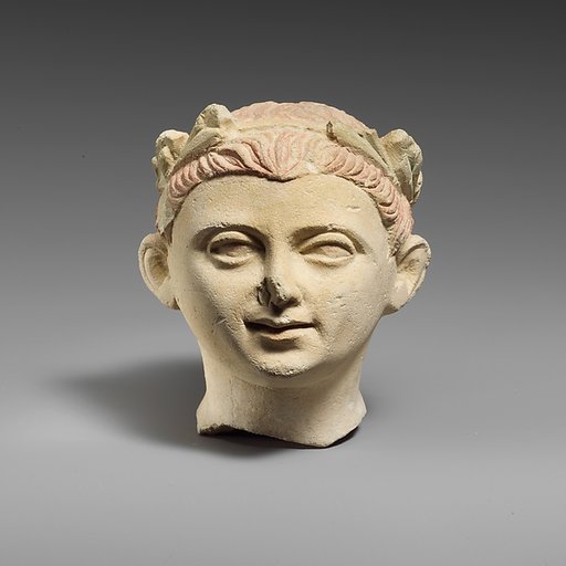 Limestone head of a boy with a wreath of leaves
