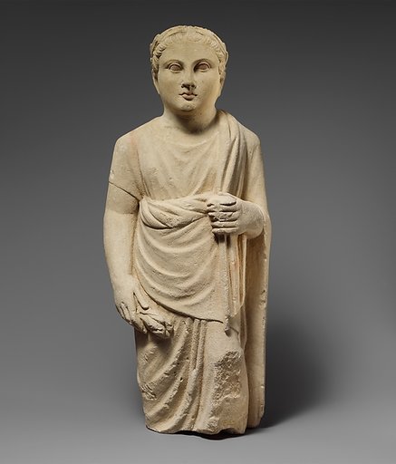Limestone statuette of a boy holding a pyxis and a branch of leaves