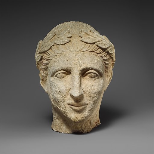 Limestone head of a beardless male votary with a wreath of leaves