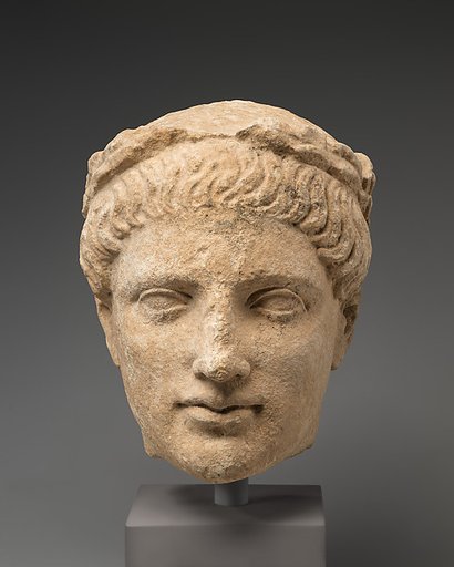 Limestone head of beardless male votary with wreath of leaves