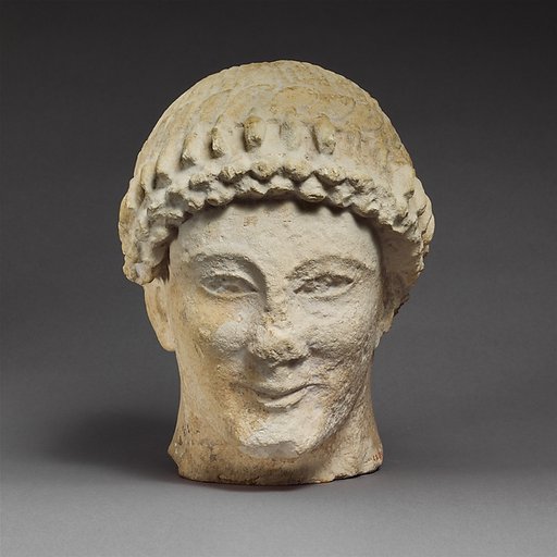Limestone head of a beardless male with a wreath of flower buds