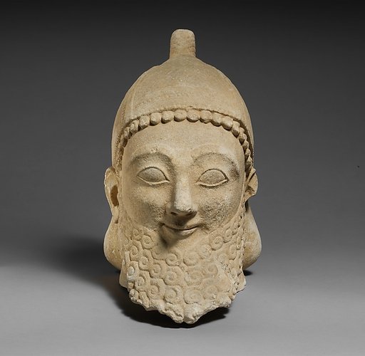 Limestone head of a bearded male wearing a conical helmet