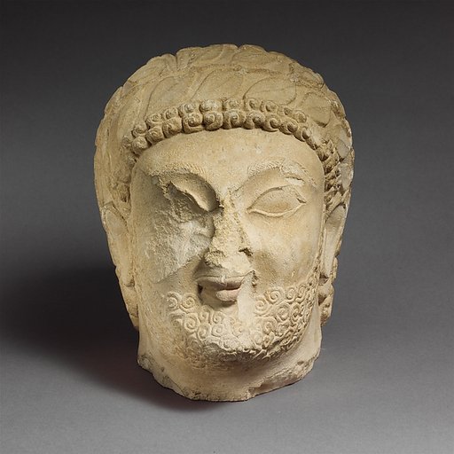 Limestone head of a bearded male with a wreath of leaves