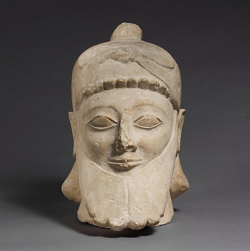 Limestone head of a bearded male wearing a conical helmet