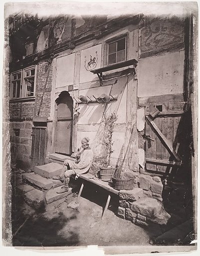 [Man Smoking Pipe Outside His Home on Village Street]