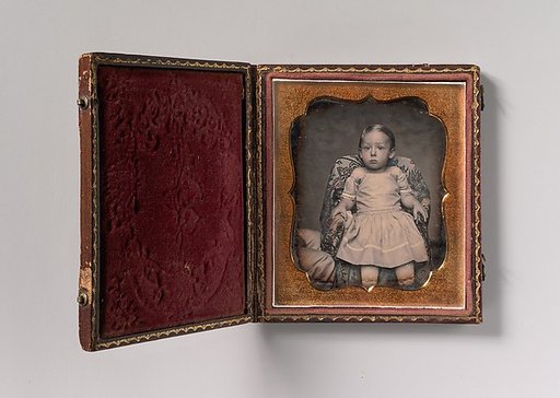 [Child Sitting on Chair Draped with Floral Print Fabric]
