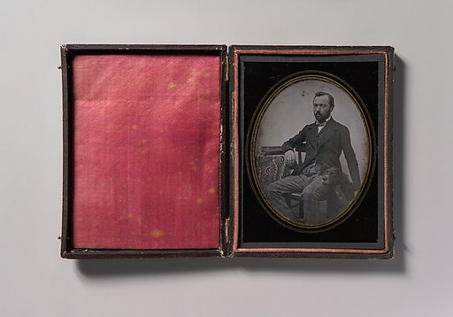 [Man Seated at Table with Dog]