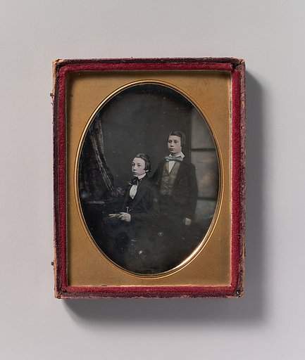 [Two Young Men in Bow Ties, One Seated Holding a Book, One Standing]