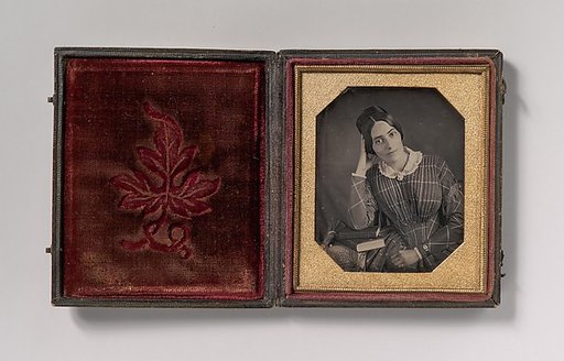 [Young Woman with Elbow Resting on Small Pile of Books and Head on Hand]