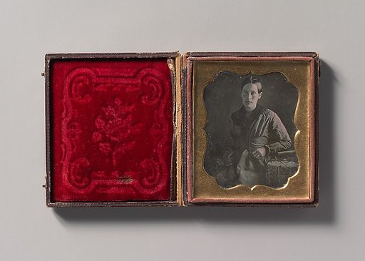 [Young Woman Seated Next to a Table with Elbow Resting on a Book]