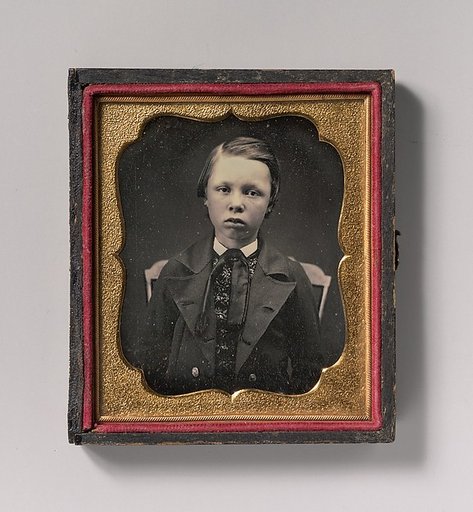 [Boy in Wide Lapelled Coat, Seated in Chair]