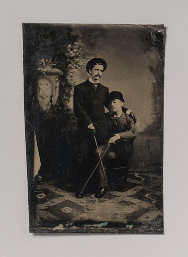 [Two Young Men Crossing Their Walking Sticks]