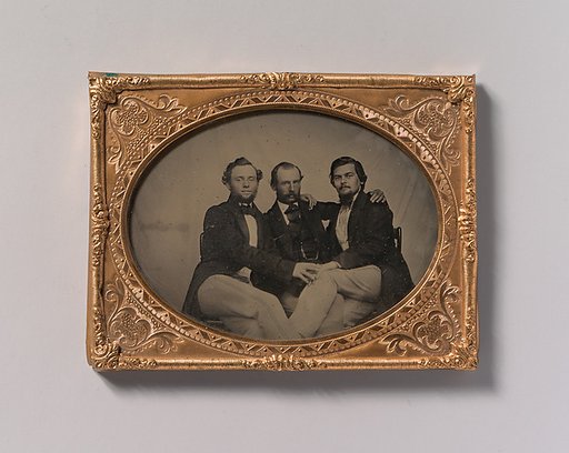 [Three Seated Men with Arms Around Each Other]