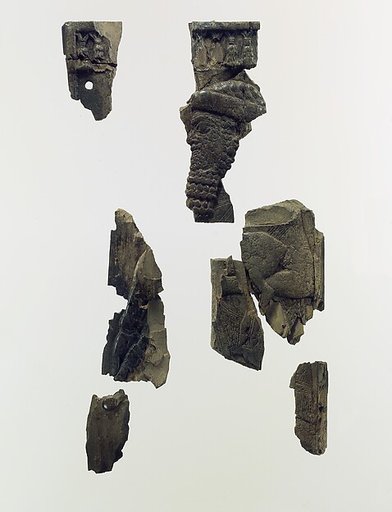 Furniture plaque fragments carved in relief with a bearded male dignitary carrying a young goat