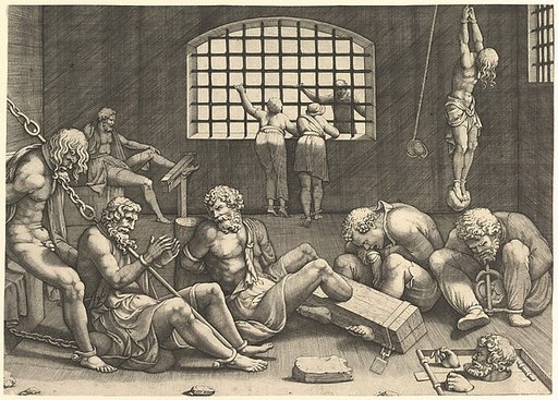 The Prison; a group of men in a dungeon bound in chains and shackles; to the right a figure hanging from his arms, tied to a boulder