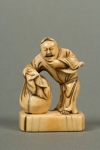 Netsuke of Man with a Bag, Standing on a Block