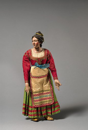 Young woman looking up in red top, green skirt, cream apron