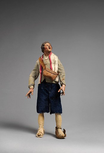 “Shepherd” looking up dressed in light green jacket, white furry vest, blue pants, leather bag