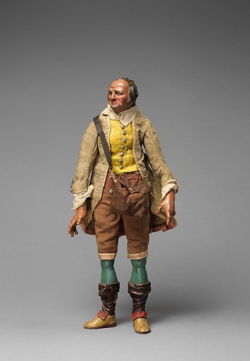 Gentleman with yellow vest, tan/maroon knickers, beige coat, falling down stockings over blue legs, and shoulder bag