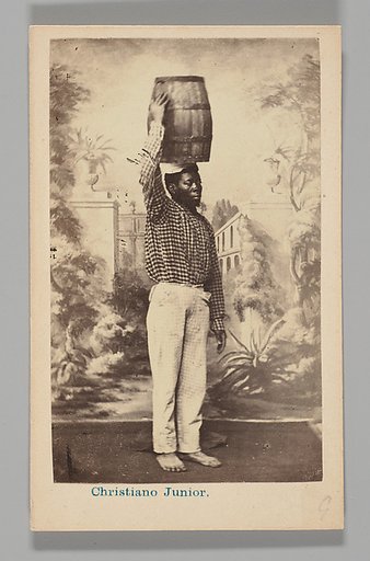 [Studio Portrait: Male Street Vendor with Barrel on Head, Brazil]