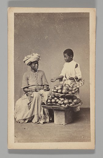 [Studio Portrait: Seated Woman and Standing Boy Street Vendors with Vegetable Baskets, Brazil]