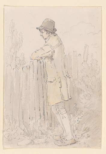 A young man leaning on a fence
