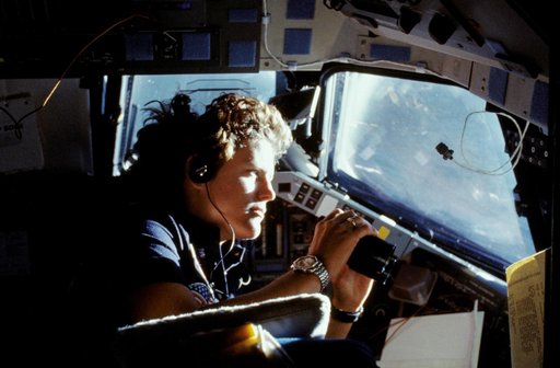 Astronaut Kathryn Sullivan using binoculars for magnifed viewing of earth