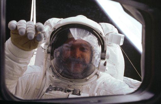 Astronaut S. David Griggs waves to Orbiter during EVA