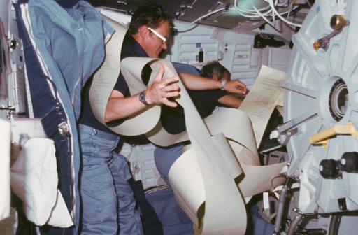 Astronauts Bobko and Williams surrounded by teleprinted messages