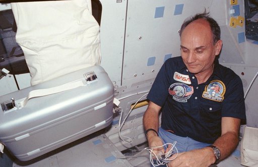 Payload specialists Sen. Jake Garn plugs in food warmer in middeck area
