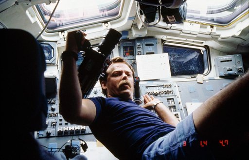 Astronaut Robert Gibson prepares to use motion picture camera