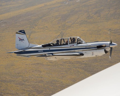 NASA Aircraft flies over yellow wildflowers abundant due to rainy winter season. The T-34 aircraft was flown from the agency's Armstrong Flight Research Center.