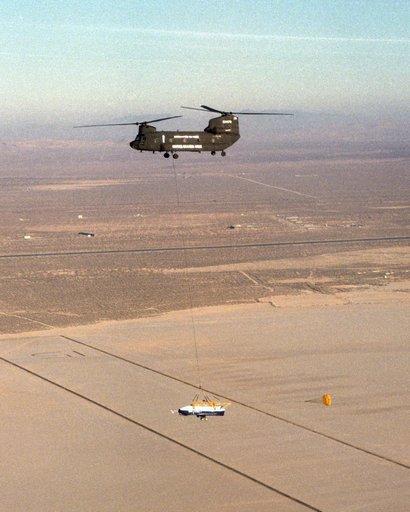 The X-40 sub-scale technology demonstrator and its U.S. Army CH-47 Chinook helicopter mothership fly over a dry lakebed runway during a captive-carry test flight at NASA's Dryden Flight Research Center