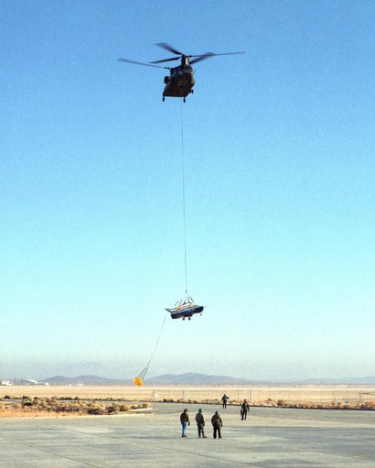A U.S. Army CH-47 Chinook helicopter slowly lowers the X-40 sub-scale technology demonstrator to the ground under the watchful eyes of ground crew at the conclusion of a captive-carry test flight