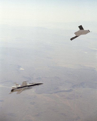 X-45A in flight with F-18 #846 chase aircraft, during first GPS-guided weapon demonstration flight