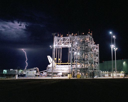 Lightning strikes in the distance as the Space Shuttle Discovery receives post-flight processing in the Mate-Demate Device, following its landing at NASA DFRC
