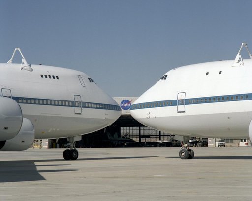 The NASA logo on a hangar is framed by the noses of NASA's two modified 747 Shuttle Carrier Aircraft on the ramp at NASA Dryden in this 1995 photo