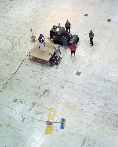 Powered by a laser beam directed at it from a pedestal, a model plane makes the first flight of an aircraft powered by laser energy inside a building at NASA Marshall.