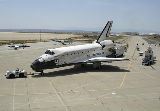 Shuttle Discovery, accompanied by recovery vehicles, is towed up the taxiway at NASA's Dryden Flight Research Center following its landing on August 9, 2005
