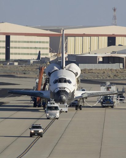 Accompanied by a convoy of recovery vehicles, the Space Shuttle Atlantis is towed up the taxiway at NASA Dryden following its landing on June 22, 2007