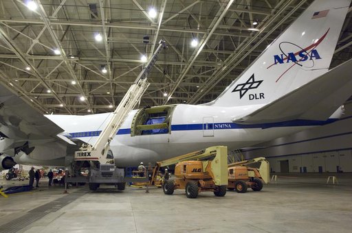 A large mobile crane and hi-lift are maneuvered into place for removal of the aperture assembly and cavity doors from NASA's SOFIA observatory aircraft