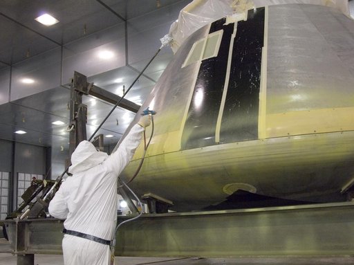 A NASA painter applies the first primer coat to NASA's Orion full-scale abort flight test crew module in the Edwards Air Force Base paint hangar.