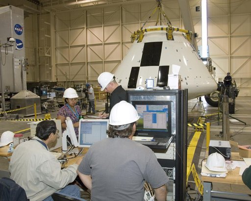 Engineers and technicians pore over data during moment-of-inertia testing on the Orion PA-1 Abort Flight Test module in the NASA DFRC Flight Loads Laboratory.