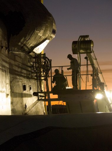 As dusk settles over Edwards Air Force Base, NASA technicians hook up various ground-support systems before shuttle Endeavour is towed off the landing runway